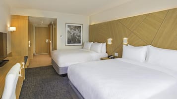 Une chambre d’hôtel avec deux lits, un bureau et une chaise.