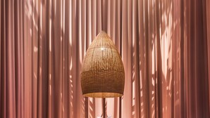 Una habitación moderna con una mesa redonda de madera, dos sillones rosados y una lámpara grande de fibra.