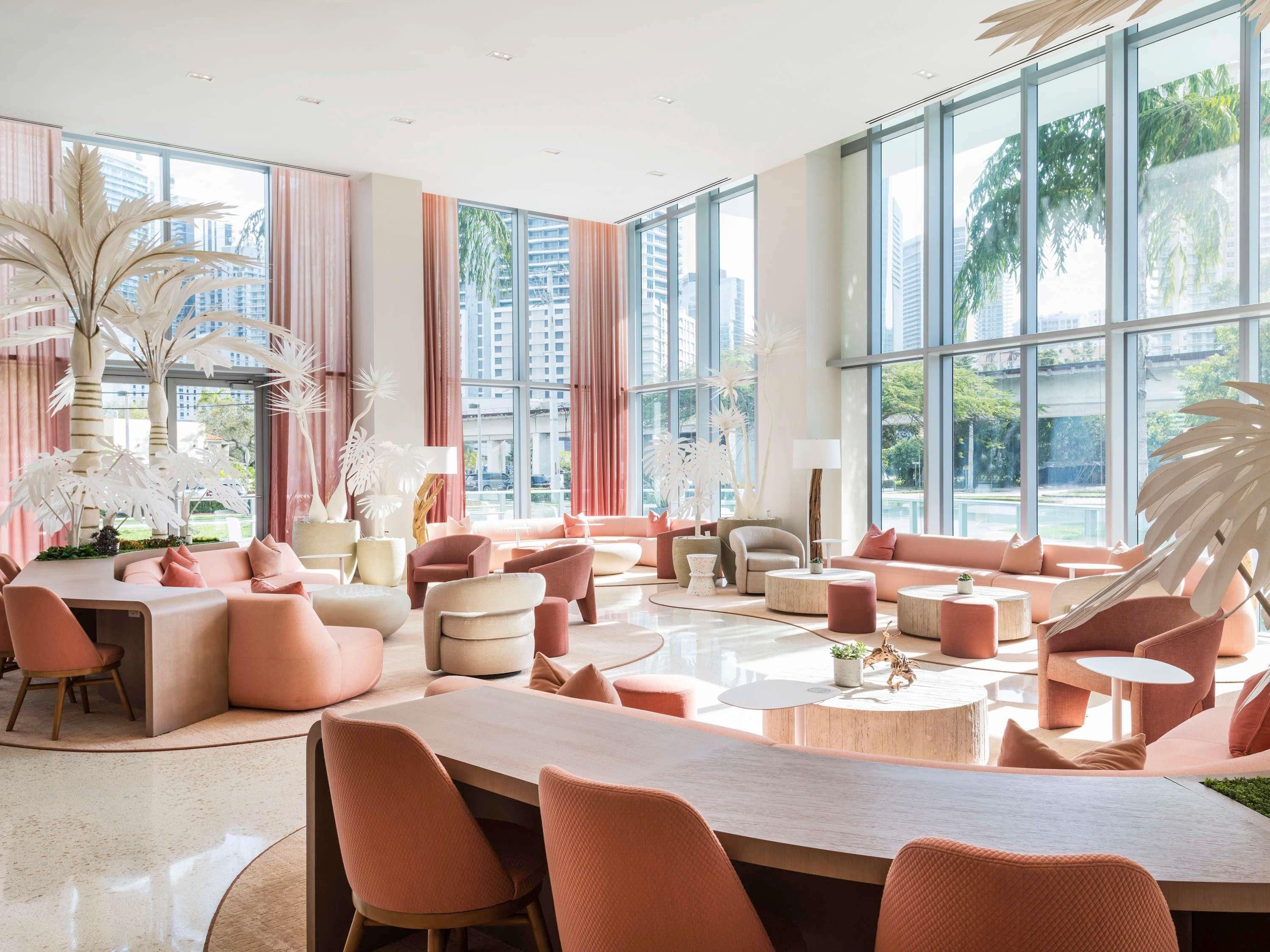 Un salón amplio con ventanas grandes, muebles modernos y plantas decorativas.