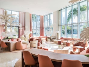 A spacious lounge with large windows, modern furniture, and decorative plants. - Novotel Miami Brickell (Miami)