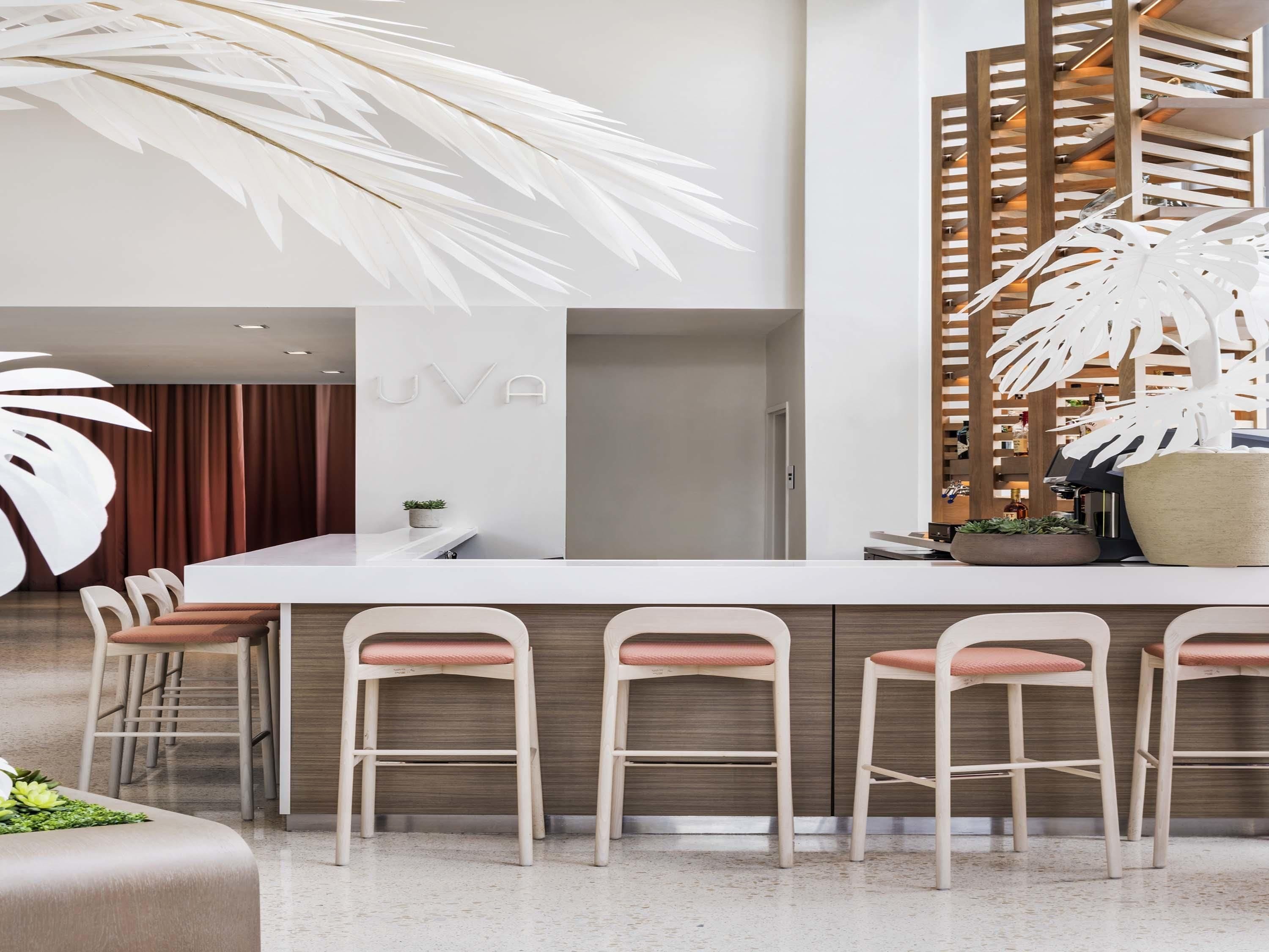 Une cuisine moderne dotée d’un îlot central, de tabourets de bar et d’une plante décorative.