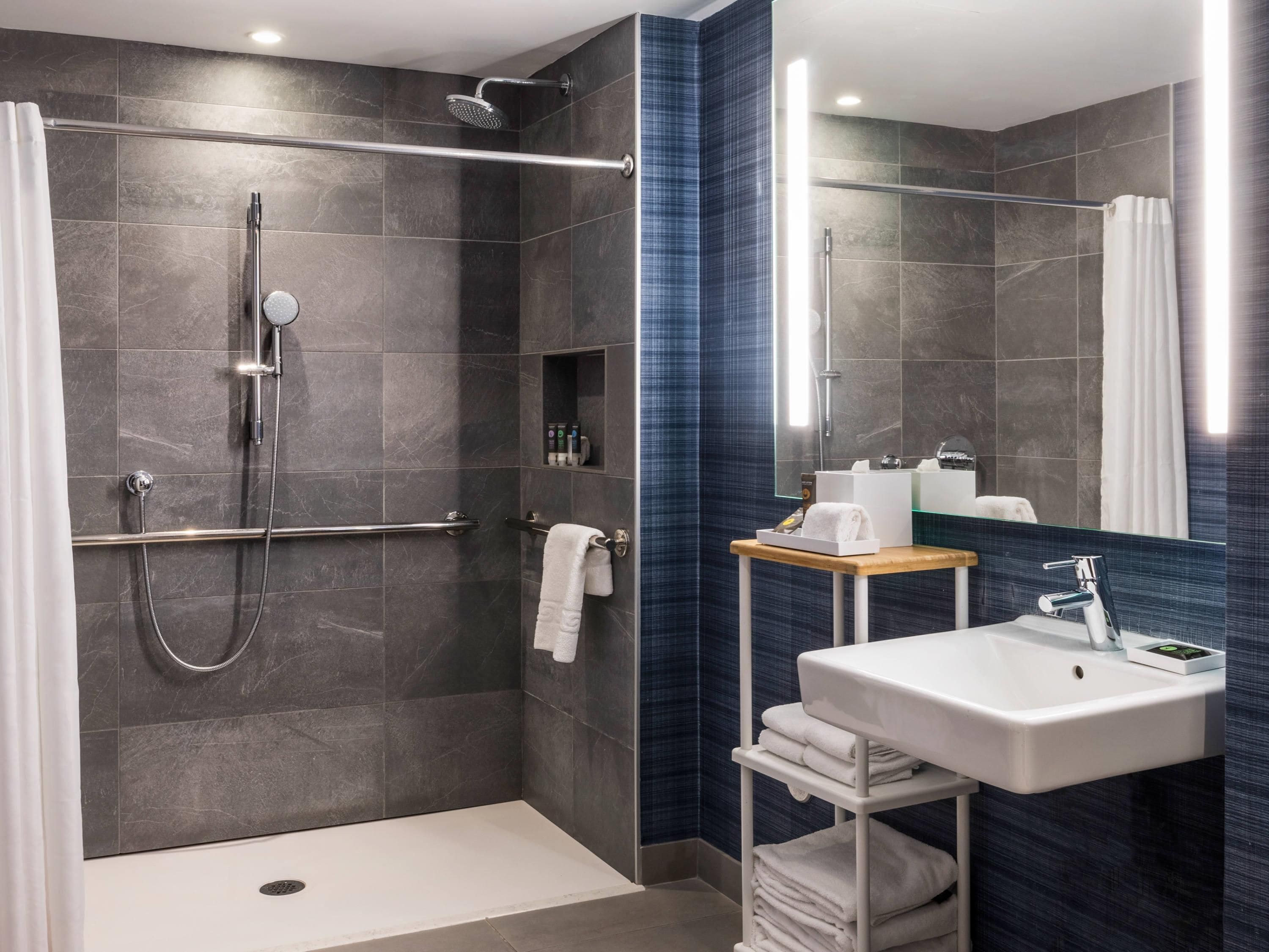 A modern bathroom with a walk-in shower, a vanity with a sink, and a mirror.