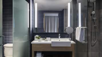 Un baño moderno con ducha envuelta en vidrio, un lavamanos blanco y un espejo grande.