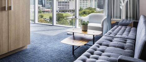 A modern room with a sofa, a small table, and a view of city buildings.