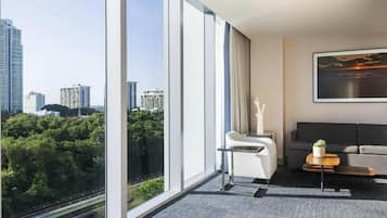 Une chambre d’hôtel moderne avec de grandes fenêtres, un canapé, une petite table et un tableau.