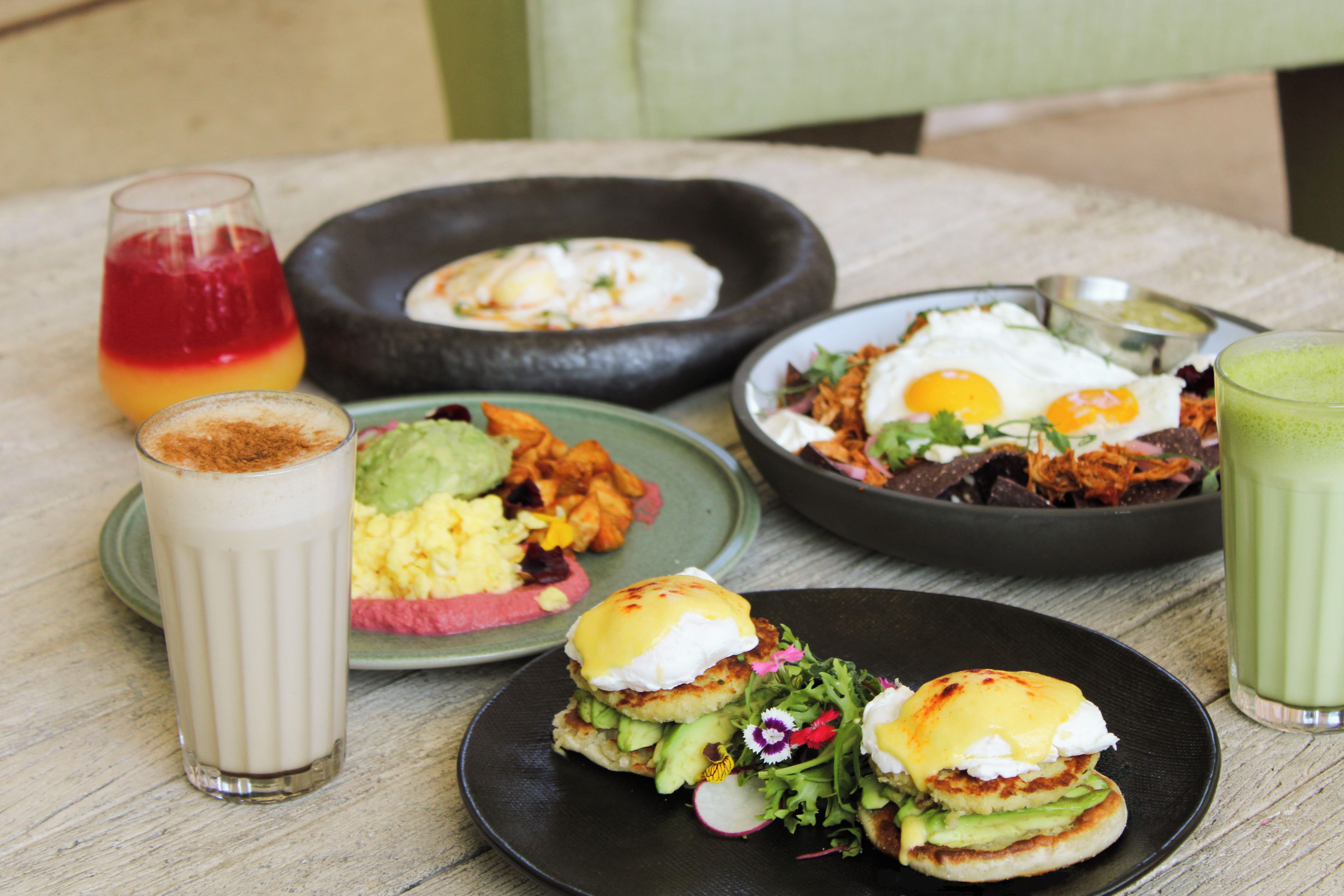A table with various breakfast items including eggs, avocado, and a green smoothie.