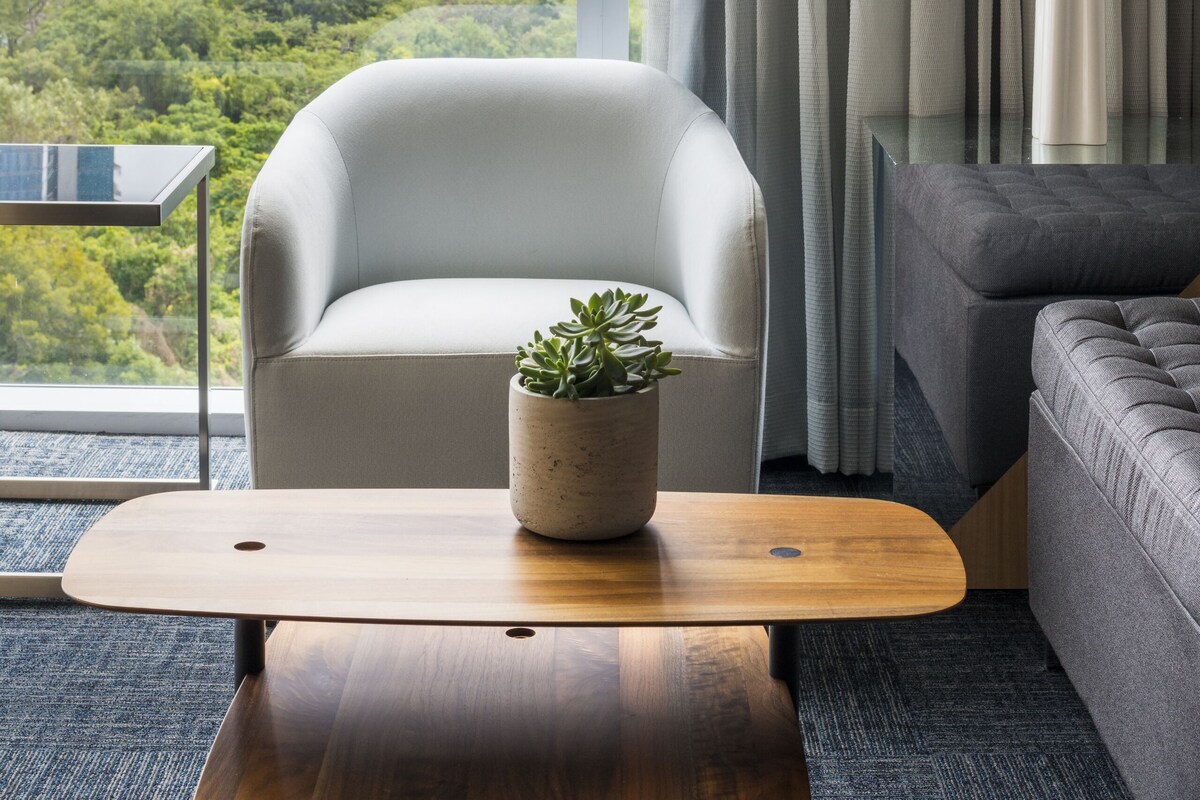 Una sala de estar moderna con vistas a un paisaje urbano y zonas verdes.