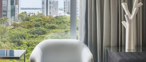 A modern living room with a view of a cityscape and greenery.