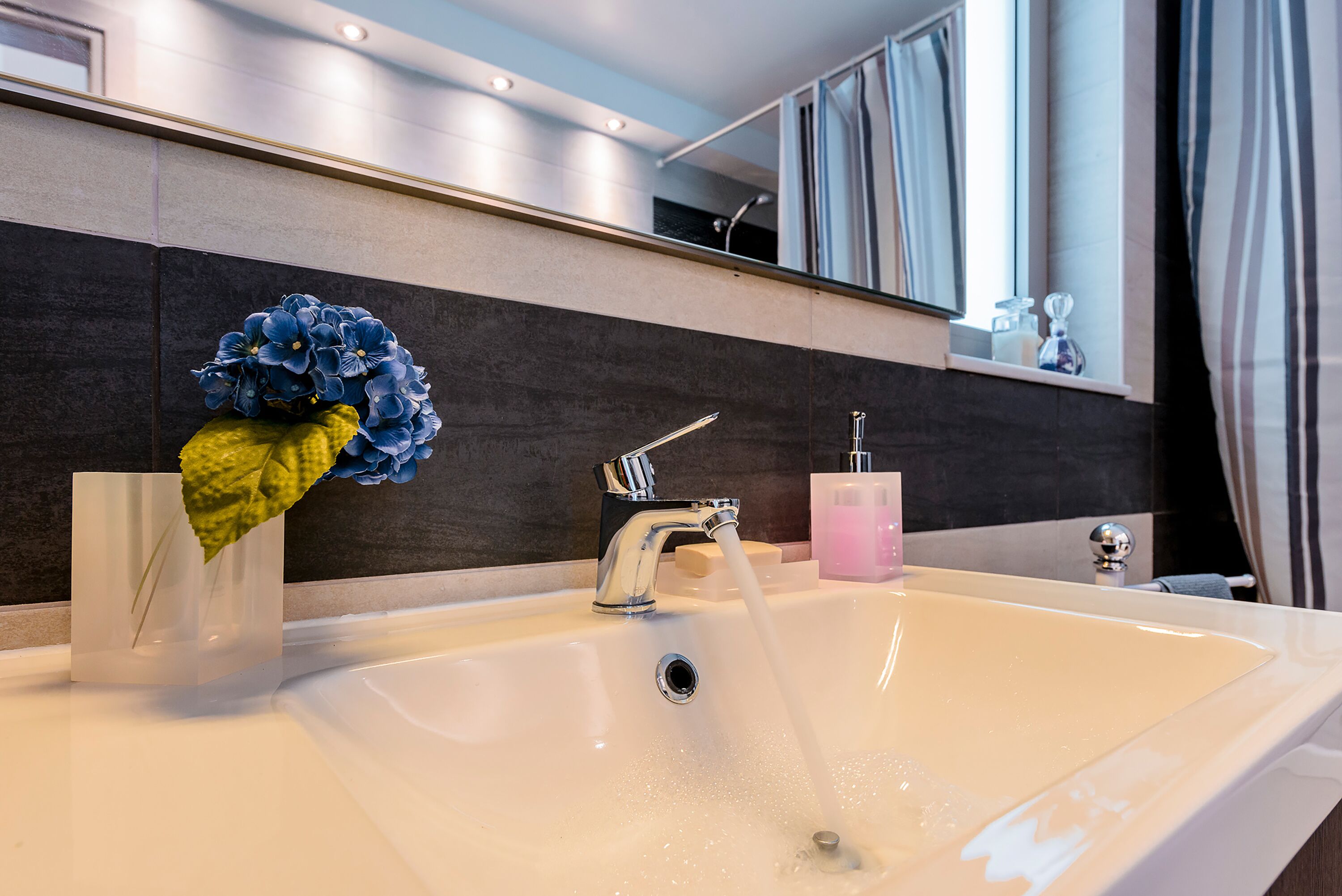 Un baño moderno con un lavamanos blanco, un grifo y un espejo encima.