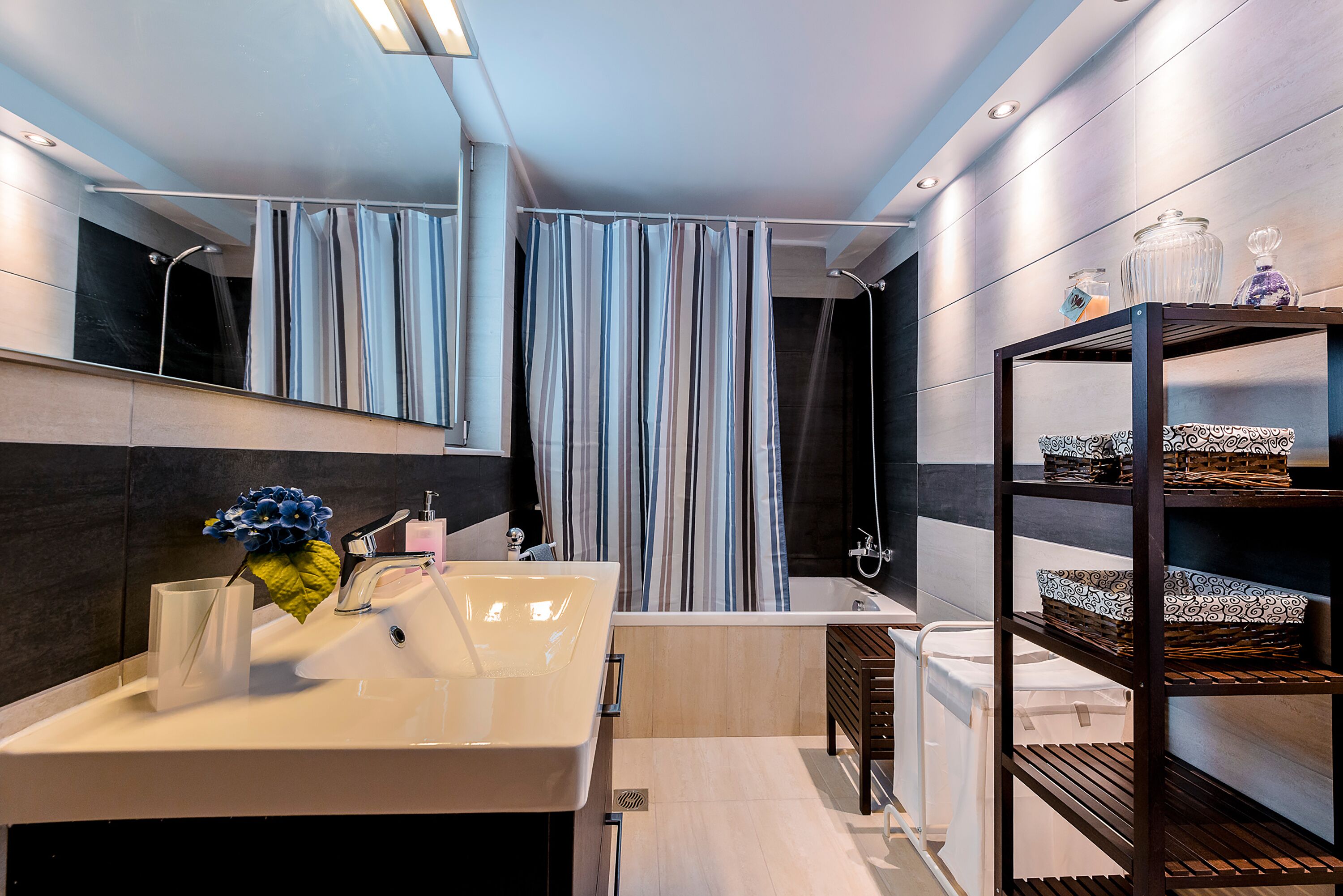 A modern bathroom with a large sink, mirror, and shower curtain.