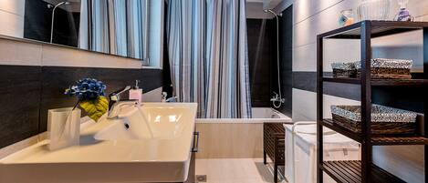 A modern bathroom with a large sink, mirror, and shower curtain.