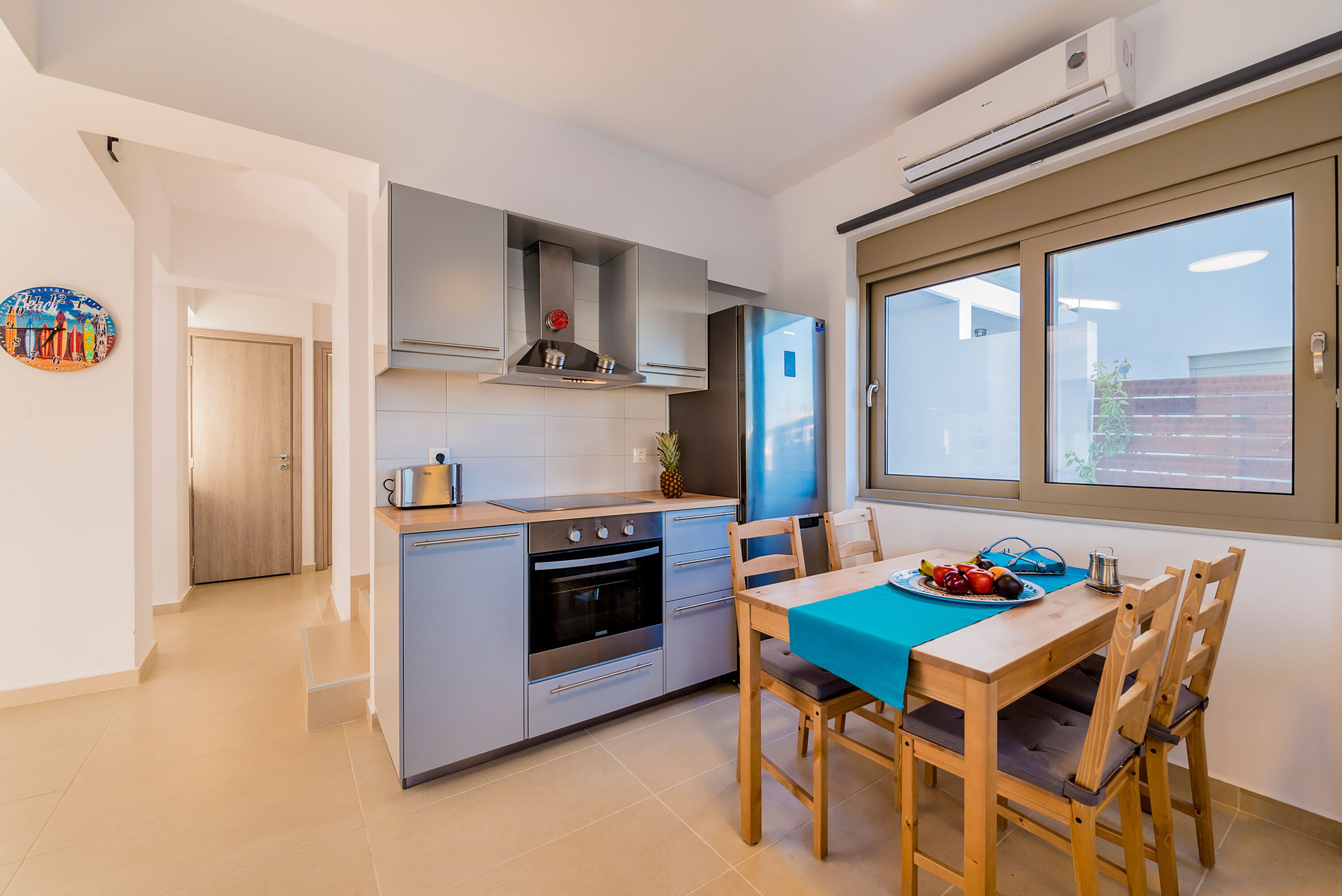 A compact kitchen with modern appliances, a dining area with a table and chairs, and a window providing natural light.