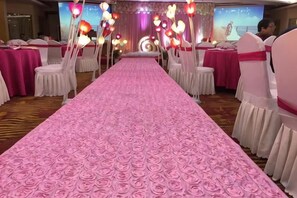 A banquet hall with a pink floral carpet, white chairs, and tables set for a formal event. - Fulaidun Business Hotel (Ningbo Airport Yadu Subway Station) (NINGBO)