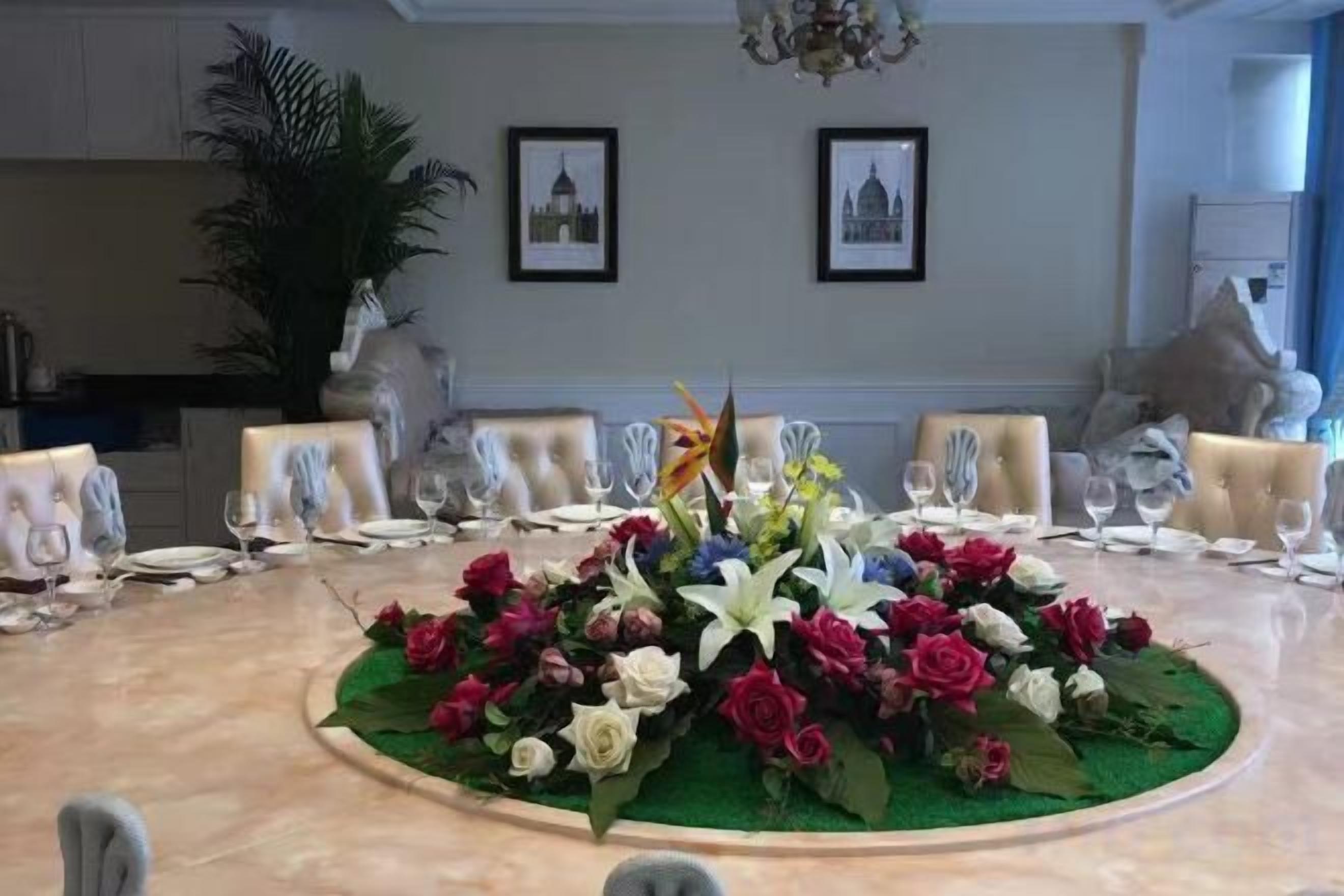 A round dining table with a floral centerpiece, surrounded by chairs.