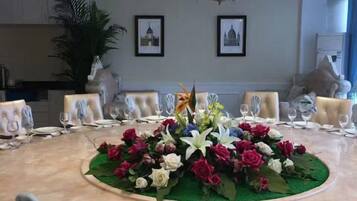 A round dining table with a floral centerpiece, surrounded by chairs.