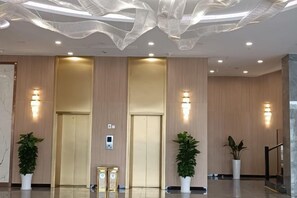 A modern lobby with two elevators, potted plants, and a decorative ceiling. - Fulaidun Business Hotel (Ningbo Airport Yadu Subway Station) (NINGBO)