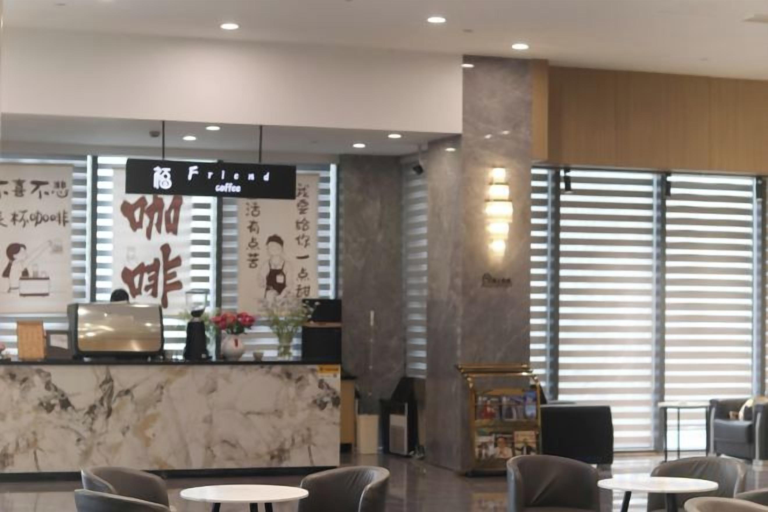 En moderne hotellobby med reception, siddeområde og store vinduer.