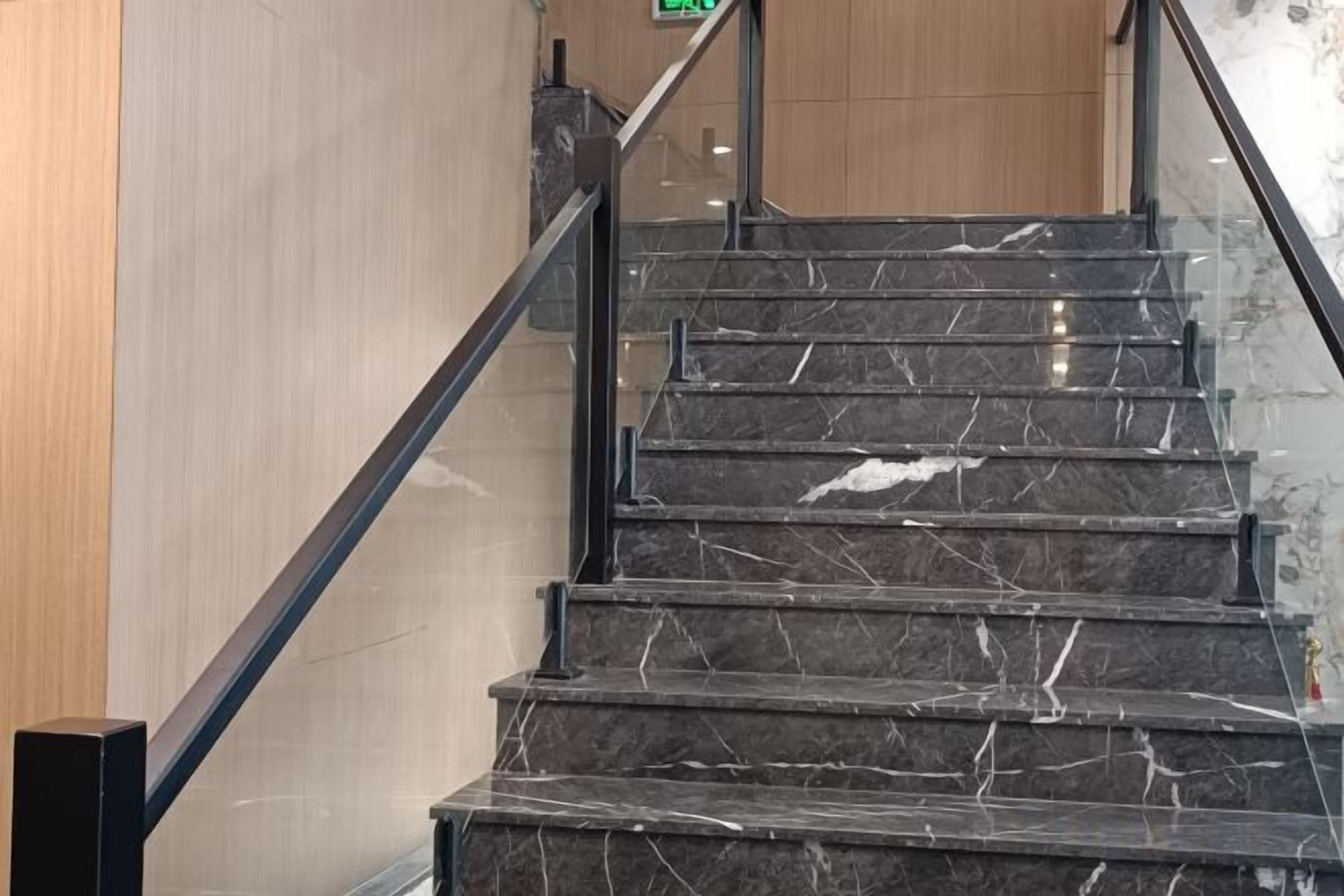 A staircase with a black handrail and marble steps.