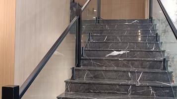 A staircase with a black handrail and marble steps.