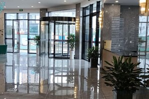 A hotel lobby with a glass revolving door, potted plants, and a marble floor. - Fulaidun Business Hotel (Ningbo Airport Yadu Subway Station) (NINGBO)