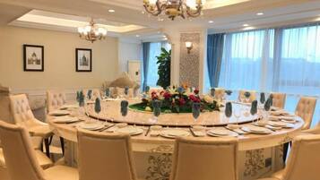 Una mesa redonda de comedor con sillas, una araña y un centro de mesa floral.