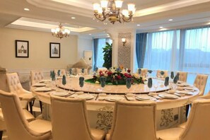 Una mesa redonda de comedor con sillas, una araña y un centro de mesa floral.