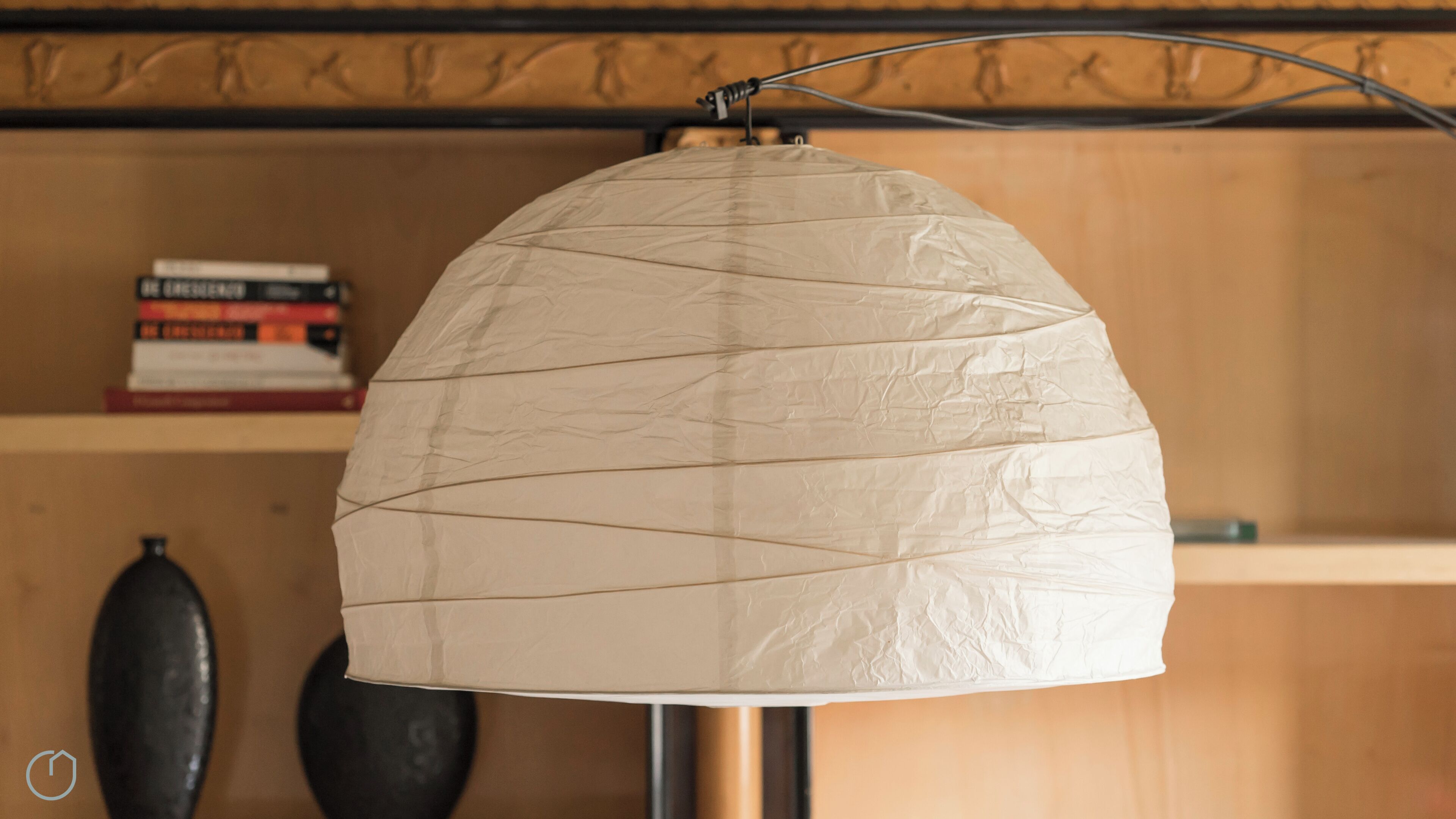 A lamp with a crumpled paper shade hanging from a metal stand.