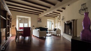 A spacious living room with wooden flooring, a fireplace, and a dining area with a table and chairs. - Italianway   - Argelati (Milan)
