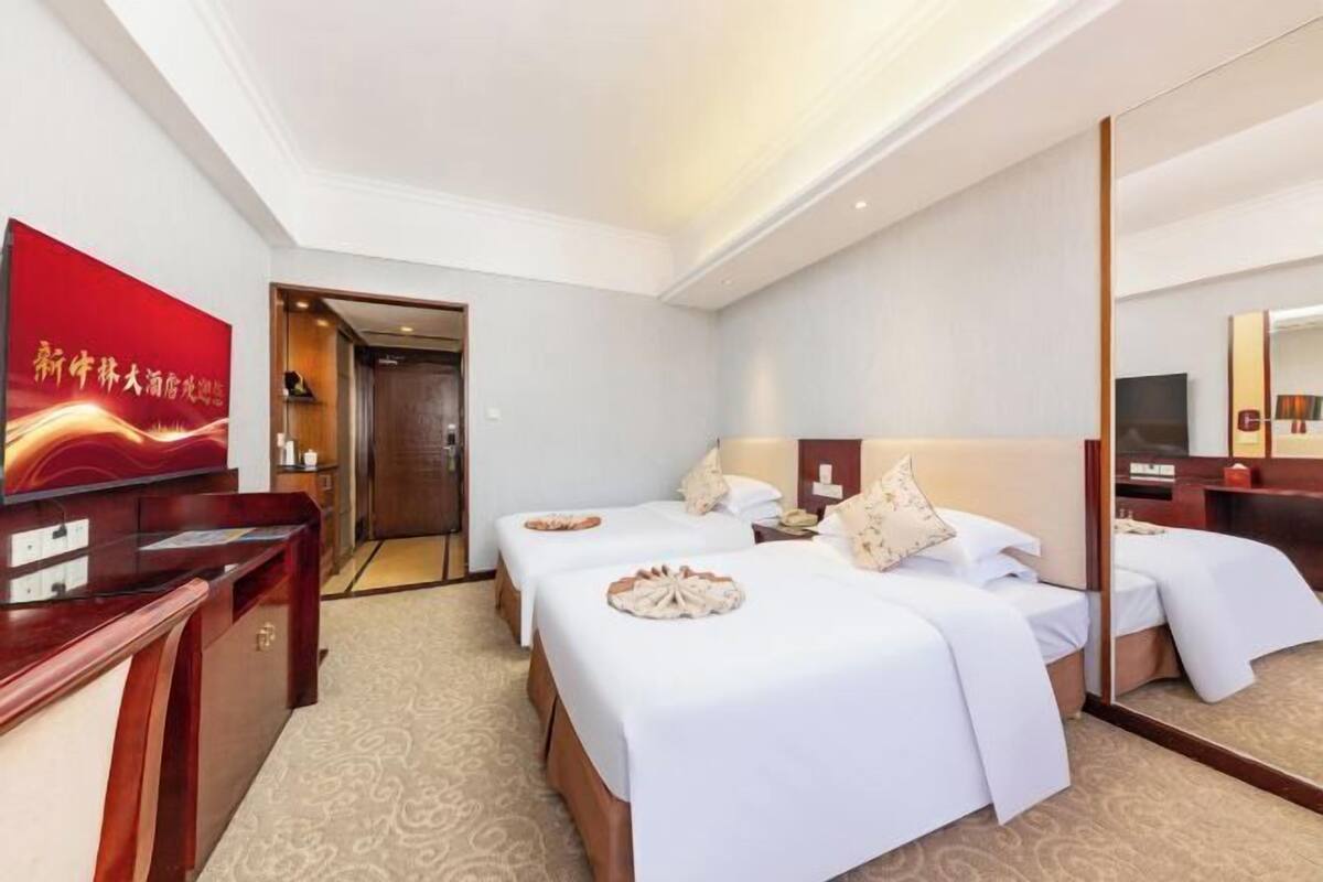 Habitación de hotel con dos camas, un escritorio, un espejo y un televisor.