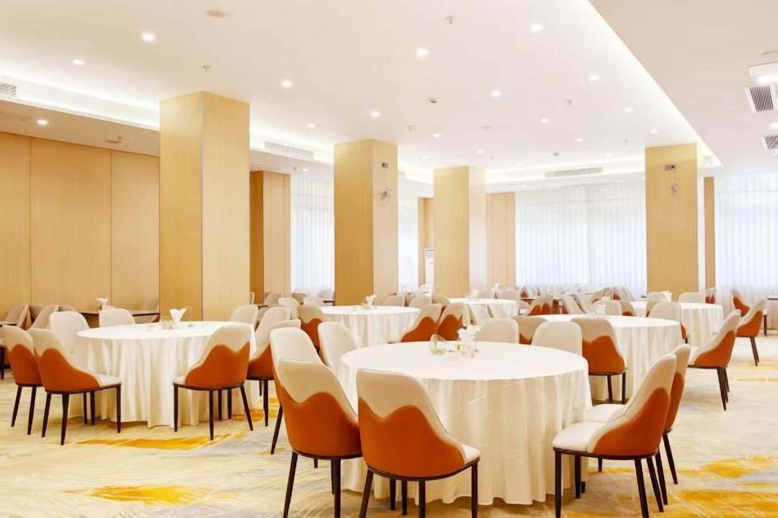 A conference room with multiple round tables and chairs, arranged in rows.