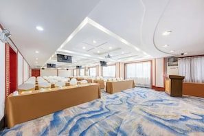 A conference room with a patterned carpet, multiple tables, and a podium. - New Forestry Hotel (Xiamen Railway Station Mingfa Plaza Branch) (Xiamen)