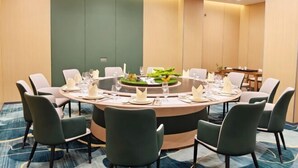 Ein Konferenzraum mit rundem Tisch, grünen Stühlen und Teppichboden.