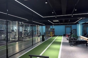 A gym with mirrored walls, exercise equipment, and a green running track. - New Forestry Hotel (Xiamen Railway Station Mingfa Plaza Branch) (Xiamen)