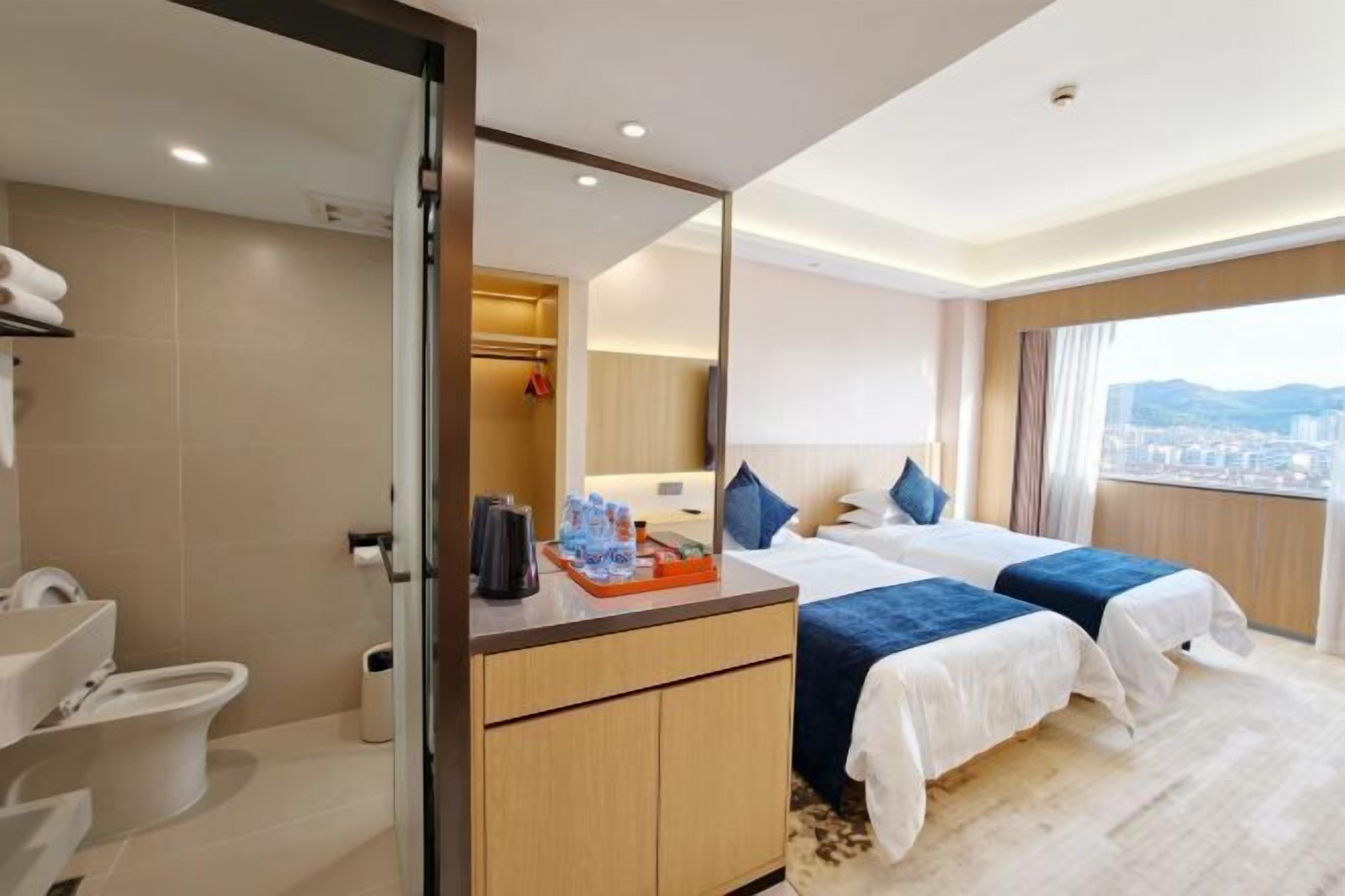 A hotel room with a bed, a bathroom, and a city view.