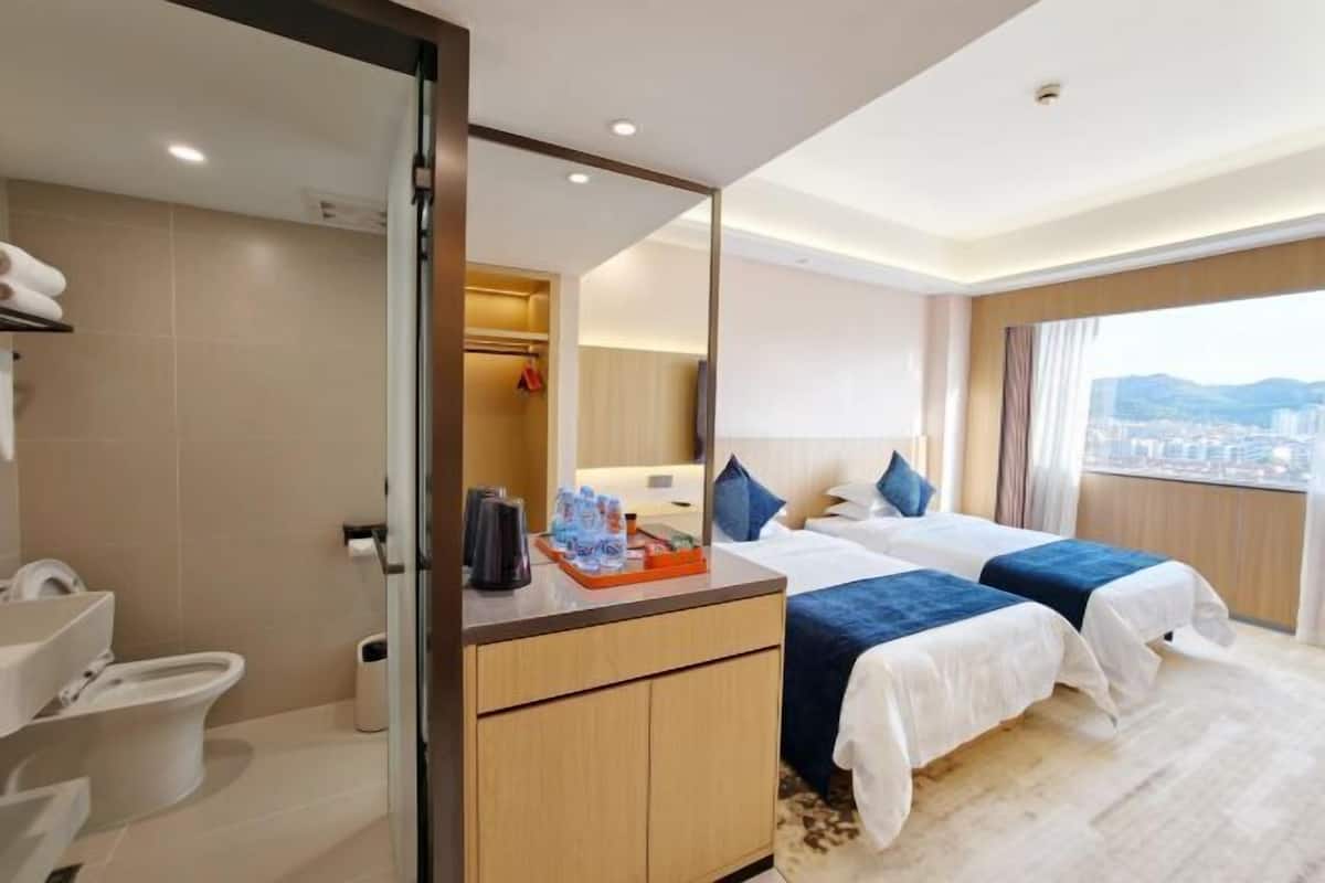 A hotel room with a bed, a bathroom, and a city view.
