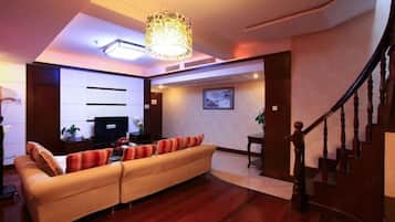 A living room with a sofa, a television, and a staircase.