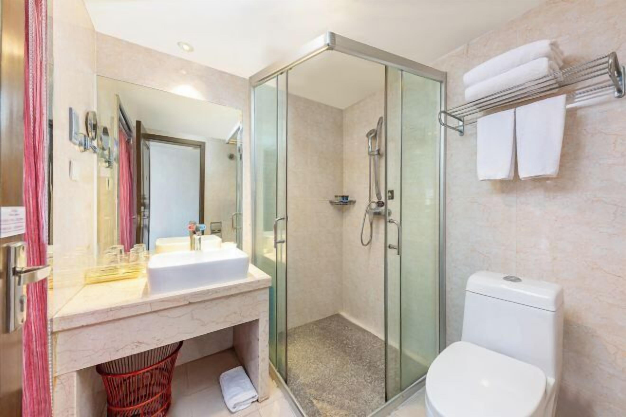A modern bathroom with a glass-enclosed shower, a white sink, and a toilet.