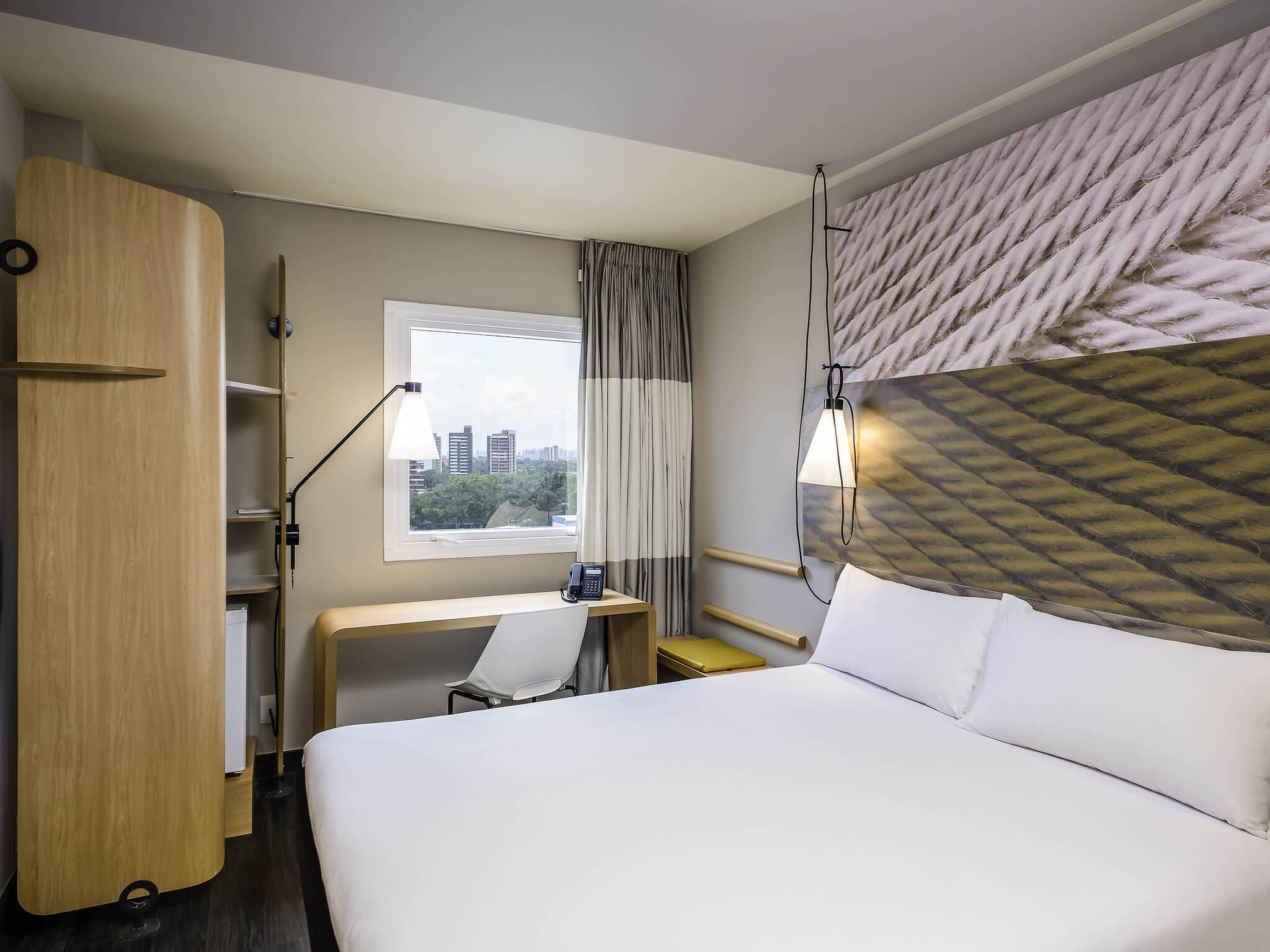 A hotel room with a bed, desk, chair, and wardrobe.