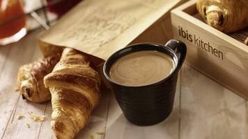 A wooden tray with croissants and a black cup of coffee.