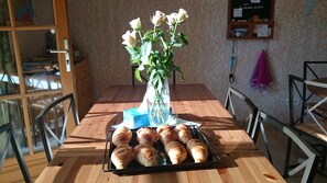 Una taula de fusta amb un ram de flors blanques, un plat de croissants i una caixa blava.
