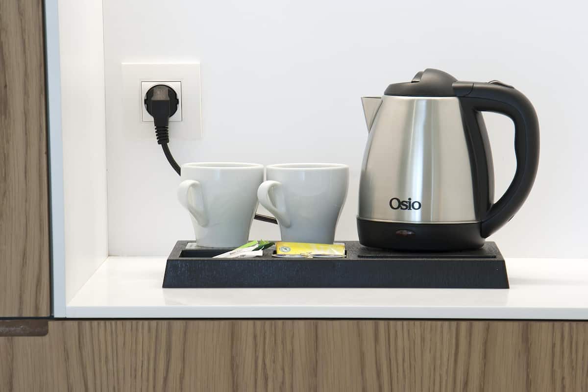 A kitchen counter with a coffee maker, two white cups, and a power outlet.