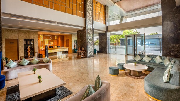 Eine geräumige Lobby mit einer Rezeption, Sitzbereichen und Blick ins Freie.