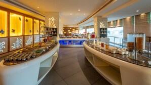 Ein Hotelbuffet mit mehreren Speiseauslagen, einem zentralen Servierbereich und dekorativen Wandverkleidungen.