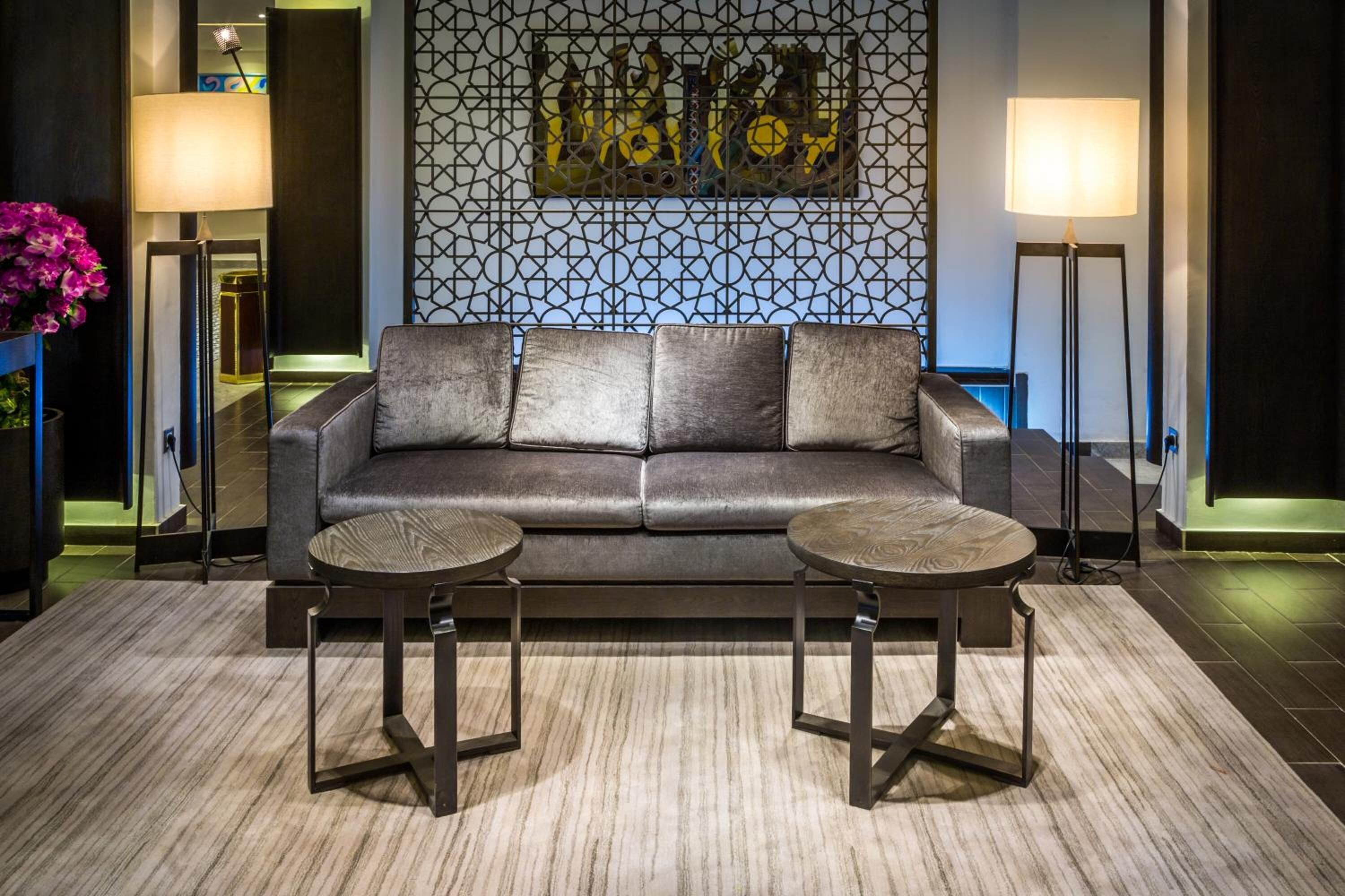 A modern living room with a dark leather sofa, two round tables, and a geometric patterned wall.