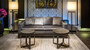 A modern living room with a dark leather sofa, two round tables, and a geometric patterned wall.