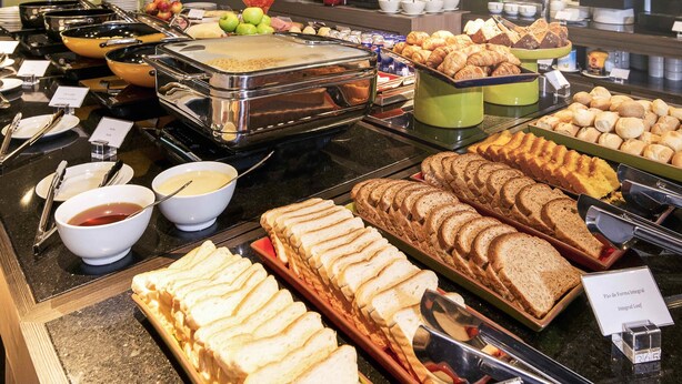 A buffet with various food items including bread, pastries, and fruits. - Novotel Santos Gonzaga (Santos)