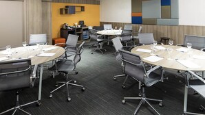A conference room with round tables, chairs, and a projector screen. - Novotel Santos Gonzaga (Santos)