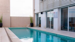 A rectangular swimming pool with a clear blue water surface, surrounded by a tiled deck. - Novotel Santos Gonzaga (Santos)