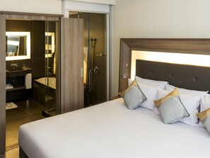 A hotel room with a bed, a bathroom with a shower, and a mirror. - Novotel Santos Gonzaga (Santos)