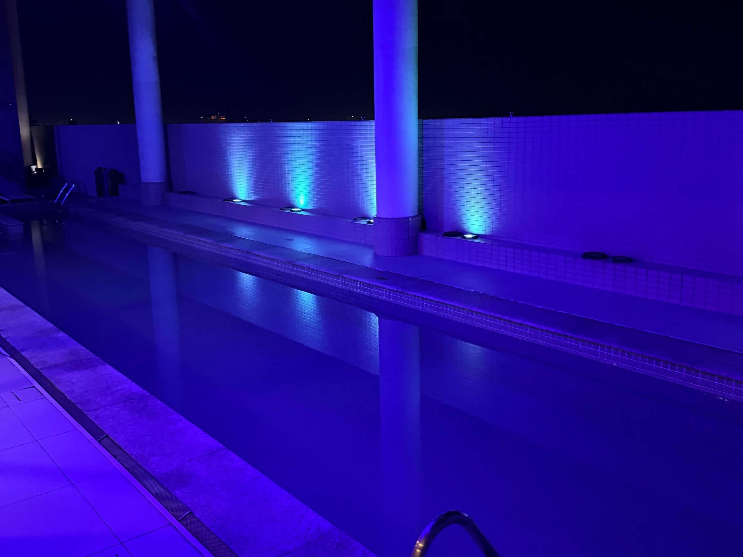A swimming pool with a tiled edge and a series of lights along the side.